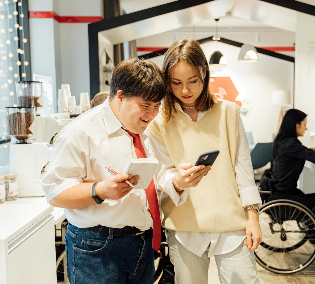 Disabled man with down syndrome looking at mobile phone with friend
