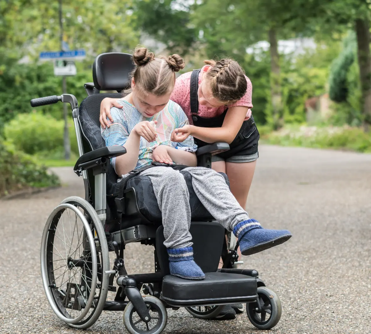 Disabled girl in wheelchair outside with friend