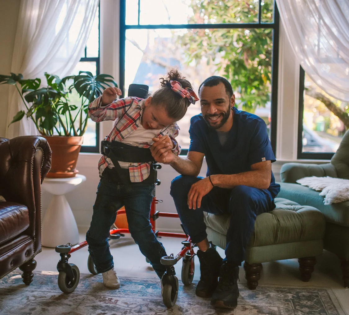 Disabled girl in walker with support worker at home